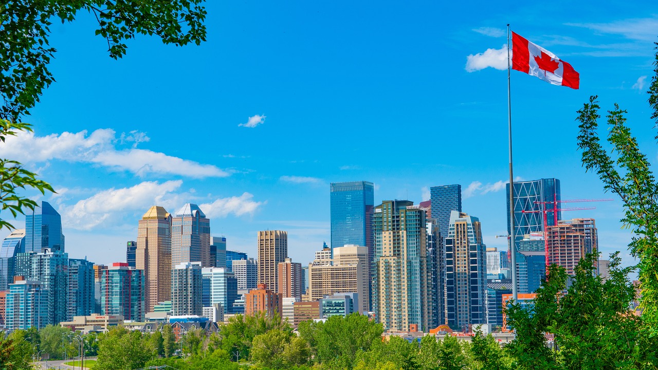 cityscape of Calgary with a Canadian flag in the foreground